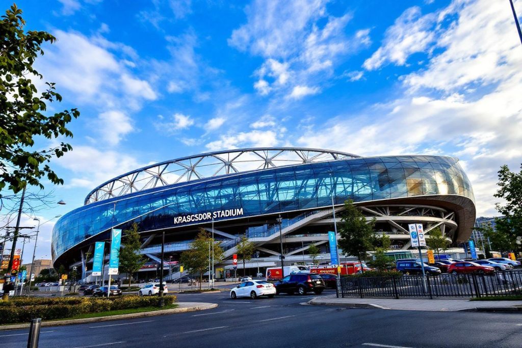 Stade futuriste bleu avec structure en verre sous ciel nuageux
